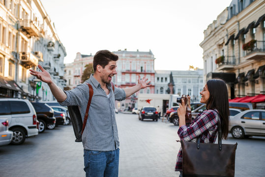 Young mixed race tourist couple taking pictures on vintage camera while walking through the city