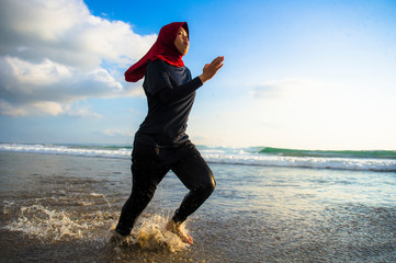 Woman wearing Muslimah Sportswear running along sea, Malaysia