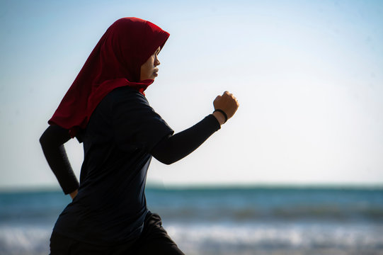 Woman wearing Muslimah Sportswear running along sea, Malaysia
