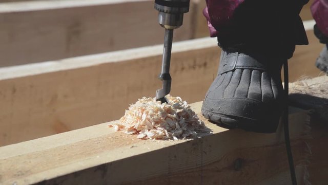 Сarpenter is Dreeling wood and hammer nail at wooden house construction.