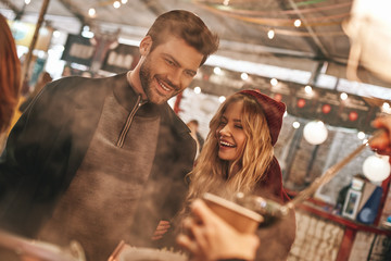 Close-up of young couple are drinking mulled wine at the street food market.