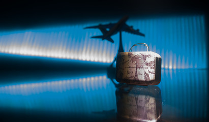 stack of traveling luggage in airport terminal and passenger plane flying over sky
