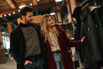 Obraz na płótnie Canvas Happy young couple choosing handmade eco fur coat at small street market