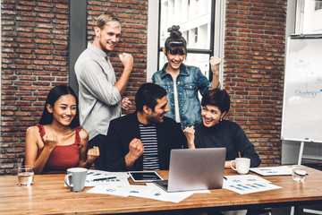 Successful of group of casual business discussing and working with laptop computer.creative business people celebrating with arms up in modern workloft.Teamwork concept