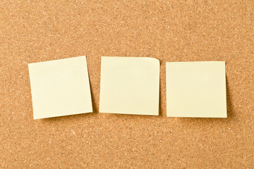 Three empty yellow sticky paper memo notes on cork board