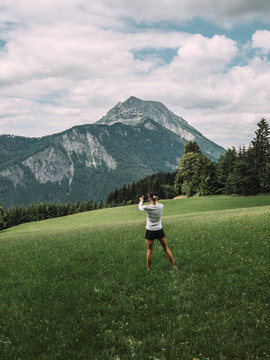 Rear view of woman taking picture of mountain peak with smartphone