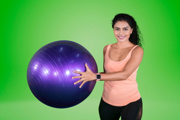 Slim woman holding a yoga ball on studio