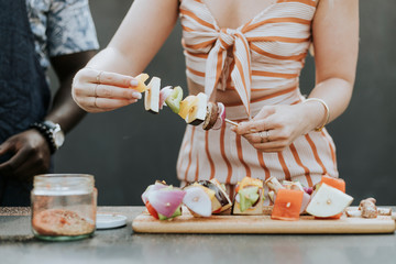 Woman making barbeque skewers for a party
