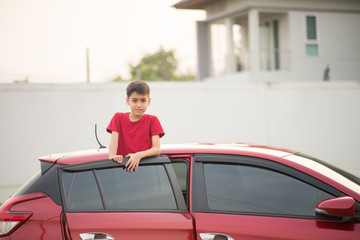 Little boy sitting on the back door of the car with ahnd wave