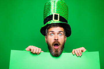 Green patricks background. Man in Saint Patrick's Day leprechaun party hat having fun on green...