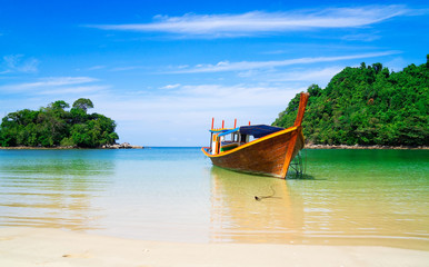 Fototapeta premium piękna sceneria z drewnianą łodzią na plaży biały piasek w błękitne morze i błękitne niebo na tropikalnej plaży.