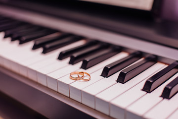 Two golden wedding rings on piano keys