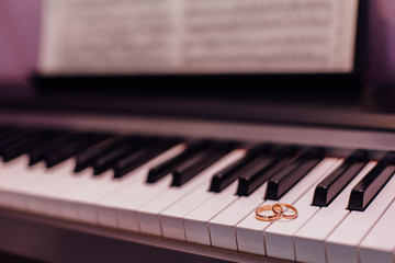 Two golden wedding rings on piano keys