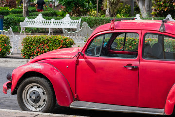 Old, classic, vintage red car in front of white benches, v1