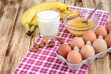 Pancakes with banana,nuts and honey on white plate for breakfast on wooden background with copy space.