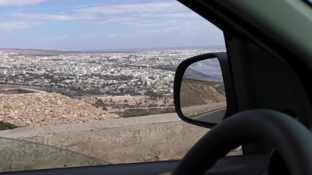 Moroccan Agadir city panorama from inside of car driving on the hillside road, high angle view