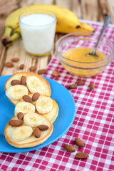 Pancakes with banana,nuts and honey on white plate for breakfast on wooden background with copy space.