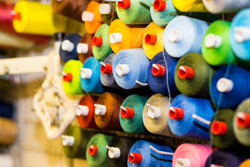 Fototapeta na wymiar Colorful cones and spools of thread at an atelier.Tailoring, garment industry, designer workshop concept. embroidery thread spool.row of multicolored yarn rolls, sewing material.Workplace of tailor