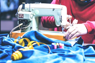 Sewing denim jeans with sewing machine. Repair jeans by sewing machine. Alteration jeans, hemming a pair of jeans, handmade garment industrial concept.
