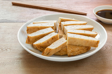 sliced of fried vietnamese pork sausage in a ceramic dish served with soy sauce on wooden table. asian food concept.