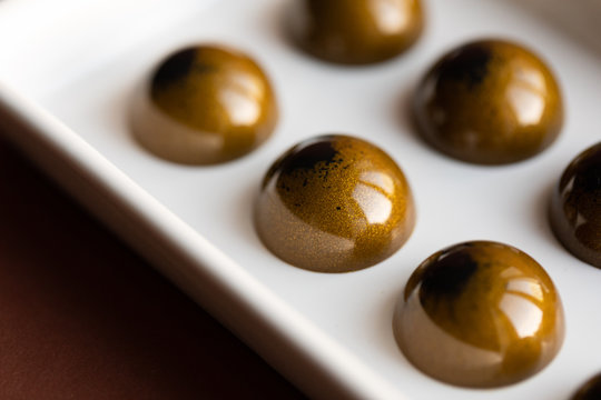 Shiny chocolate Bonbons on brown background