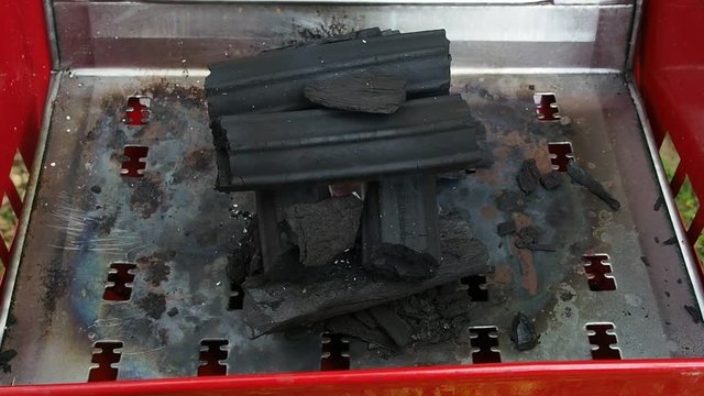 Smoke and burning charcoal in stove for barbecue at picnic.