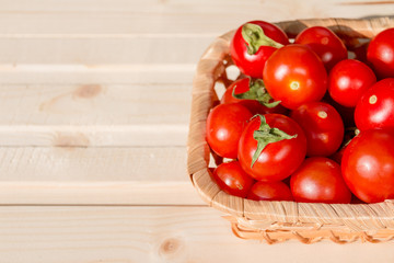 Many tomatoes called cherry tomato in the basket on wooden table, fresh organic vegetables freshly harvested from local farmers.ripe tomatoes in wicker wooden bowl.Copy space