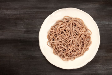 A photo of a plate of soba, buckwheat noodles, shot from the top on a black background with copy space