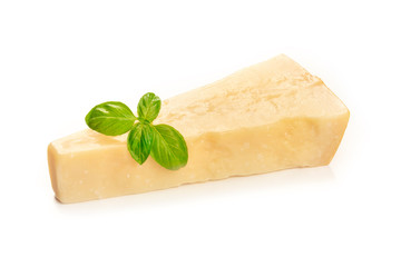 A piece of aged Parmesan cheese with fresh basil leaves on a white background with copy space