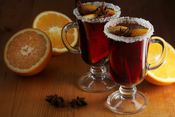 Two cups with ready mulled wine with anise, cinnamon and nuts around