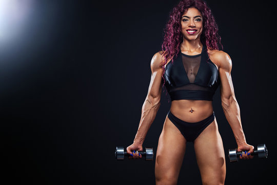 First egyptian and muslim woman athlete with dumbbells makes fitness exercising on black background with lights.