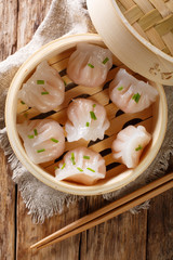 Chinese prawn dumplings dim sum placed in a bamboo steamer. Vertical top view © FomaA