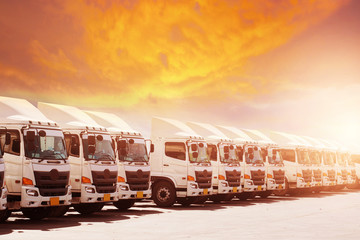 New haulage truck fleet is parking narrow at yard with sunset warm tone beautiful sky.