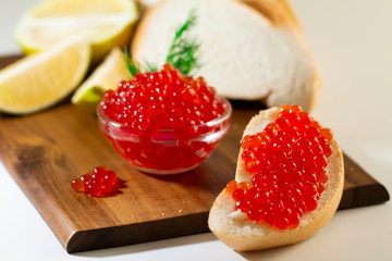 red caviar in glassware on wooden background with space for text