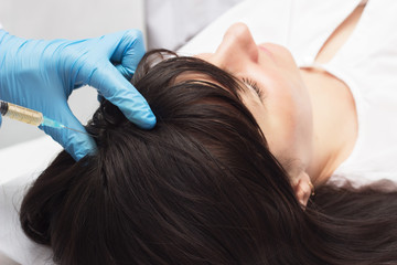 Doctor introduces plasma-lifting injection to the patient to improve the quality and beauty of the hair, close-up, plasma therapy