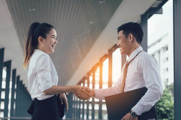 Two asian business people standing and shaking hands with together.