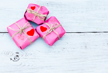 pink gift wrapping with red hearts on wooden background