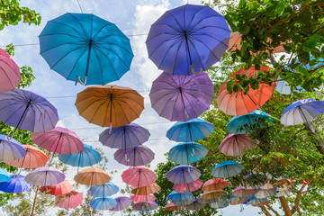 Fototapeta na wymiar Many multiple colors umbrella with blue sky background decorate in the park. summer festival