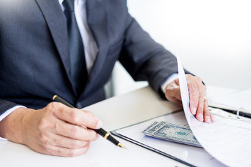 Businessman receive money in the envelope offered in file taking bribe and signing a contract -...