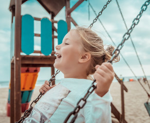 Kind schaukelt am Strand auf dem Spielplatz
