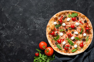 Tasty pizza with tomatoes and mozzarella on black background. Top view, copy space for text. Hot...