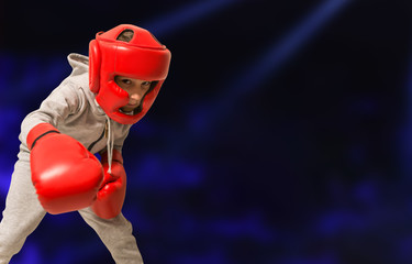Little boy in boxing gloves on ring training. Copy space. Dark background