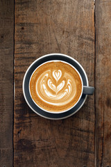 a cup of latte art coffee on wooden background