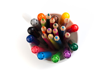 Set of markers in a paper cup and a piece of paper on white background. Top view.