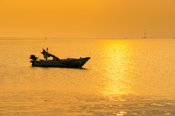 Beautiful sunrise on the beach and silhouette of fishing boat.Thailand.