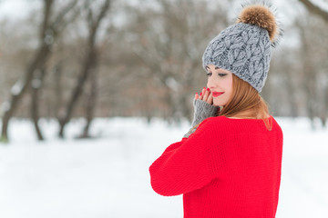 Woman in knitted red sweater and grey hat, gloves, casual ladies style, winter walks outdoor 