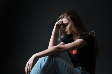 Woman sitting strain unhappy In a dark room