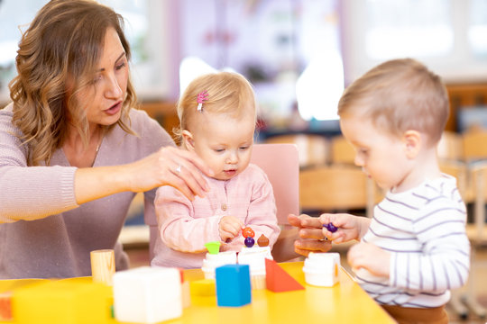 Nursery teacher with children boy and girl learn color and size while playing together. Early education concept.