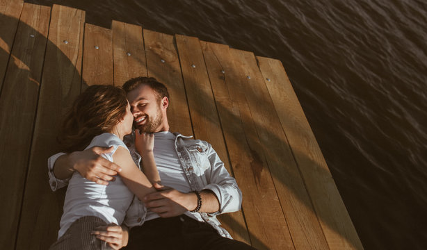 Cuddling young couple lying on pier