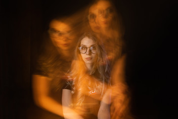 Girl with schizophrenia covering her ears to not hear the voice of her alter ego. Blurred person